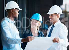 Architect, engineer and building contractor looking at plans or blueprints while talking and discussing strategy. Team or group of builders looking motivated and ready to develop, renovate or remodel