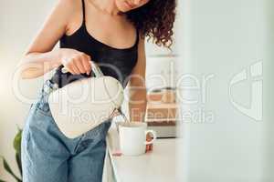 Woman making a cup of tea for breakfast before starting her morning at home. Female trying a health cleanse with organic green tea, beginning a slimming detox or diet with a healthy drink