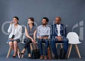 Did she get the job. Studio shot of a group of corporate businesspeople waiting in line against a gray background.