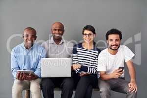 Being productive while sitting around. Studio shot of businesspeople using wireless technology against a gray background.