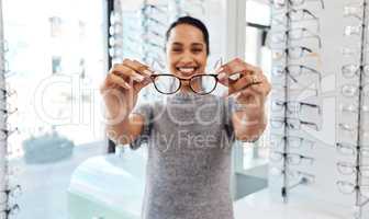 Female holding pair of trendy new glasses, stylish spectacles and prescription lenses at an optometrist. Portrait of a customer choosing, buying and shopping for frames for better vision and eyesight