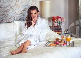 Breakfast just makes my day. an attractive young woman enjoying a luxurious breakfast in her room.