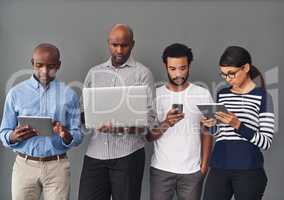 Using different defices but connected to the same network. Studio of businesspeople using wireless technology against a gray background.