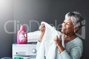 This is what perfection smells like. a mature woman smelling freshly washed towels while doing laundry at home.