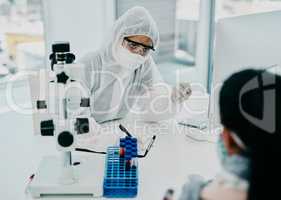 Covid and disease healthcare worker wearing hazmat suits in a consultation. Doctor writing a medical report about a corona case patient or statistics and writing a form for a safety virus check