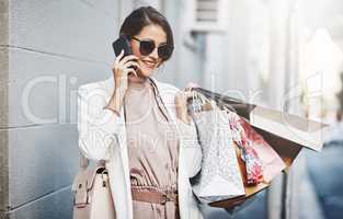 Trendy, stylish and fashionable woman shopping, purchasing and buying clothes in city, town and downtown. Elegant lady talking on phone with gift bags, going on spending spree or doing retail therapy