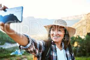 . Hiking, tourist and woman taking selfies, photo and video call for social media while exploring, travel and sightseeing in nature outdoors. Happy, active and free female enjoying scenic fresh hike.