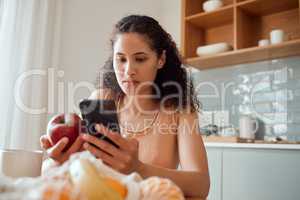 Eating healthy, diet planning and personal online female dietitian. Serious nutritionist check phone, snack on fresh fruit and concentrating on social media. Communicate with patient about calories.