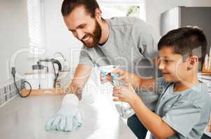 Cleaning, bonding and caucasian father and son working together to keep the home tidy. Chores, learning and a happy childhood with dad spending quality time with his boy as they clean the kitchen.