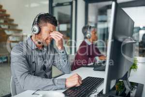 The day has brought some tension with it. a mature man looking stressed out while working on a computer in a call centre.