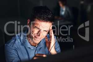 Feeling overworked and the headache is proof. a young attractive businessman working late in the office.