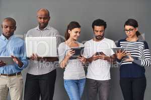 Using multiple devices to get information from multiple websites. Studio shot of businesspeople using wireless technology against a gray background.