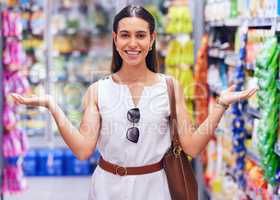 Shopping, retail and consumerism with a female customer standing in a grocery store, shop or supermarket aisle. Portrait of a young woman gesturing with products packed on shelves in the background