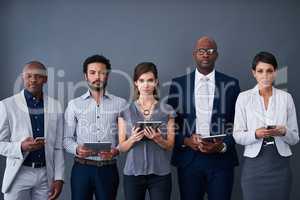Market your business the technological way. Studio shot of a group of corporate businesspeople using different devices against a gray background.