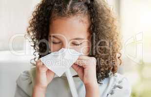 Sick, cleaning nose with tissue and tired girl kid suffering from flu virus, cold or covid at home. Closeup of a young child with a bad allergy or coronavirus sneezing with a sinus headache
