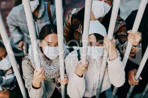 Covid travel ban, lockdown or border control to prevent spread of pandemic virus, contagious disease or illness. Portrait of prisoners in masks facing racism and discrimination behind locked gate