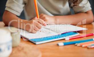 Child coloring, drawing and doing art activity in book in home living room while having fun, enjoying and feeling playful. Closeup hands of small, little and young creative girl expressing with color