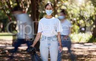 Woman in covid face mask cleaning the park for clean, hygiene and safe green environment. Responsible activist, volunteer or community service worker with rubbish, trash and garbage in a plastic bag