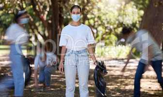 Volunteers, hygiene and environmental team cleaning a park in covid masks together. Development, energy and recycling activists working in collaboration to put messy dirt in plastic bags and trash