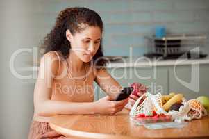 Diet, healthy mindset and health food of a female doing apple research on a phone.Young woman nutritionist at home reading weight loss, cooking and nutrition holding online fruit in a kitchen