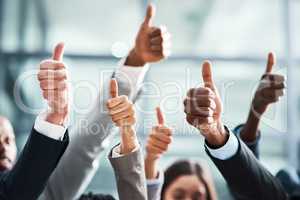 Keep up the great work. Closeup shot of a group of businesspeople showing thumbs up in an office.