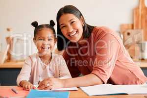 Mother helping, teaching and educating daughter with homework at home. Portrait of happy, loving and smiling mom and little girl busy with educational lesson, tutoring or assistance at home together