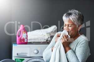 Nothing comes quite as close to that scent. a mature woman smelling freshly washed towels while doing laundry at home.