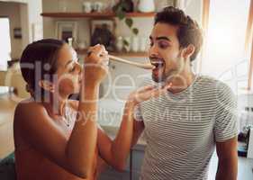 Fun, bonding and a couple cooking in a kitchen at home, enjoying free time on weekend. Young girlfriend and boyfriend learning to cook together while being playful, having fun with their relationship