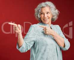 Portrait of mature woman, smiling and pointing with a gesture of affirmation, with a red background. Beautiful, confident and happy senior lady standing, index fingers pointed in positive motivation.
