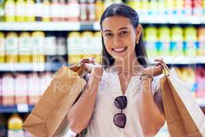 Portrait of satisfied woman shopping for groceries, smiling as she buys at the supermarket. Cheerful, young and shopaholic caucasian woman purchasing in store, buying food and products for sale.