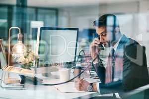 Busy with an important deal over the phone. a focused young businessman making a call while being seated inside of the office.