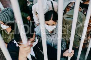 Covid travel ban, lockdown or border control to prevent spread of pandemic virus, contagious disease or illness. Travelers in masks facing quarantine, abuse and discrimination behind locked gate