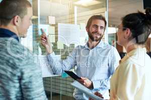 Ive worked in out and this is our best option. a group of businesspeople brainstorming with notes on a glass wall in an office.