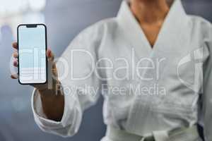 . Blank phone screen and copyspace with a karate student holding the mobile display indoors. Sport person showing a copy space announcing a sale, marketing or social media advertising content.