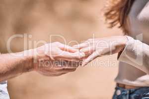 Engagement, proposal and romance while putting a ring on the finger of a woman saying yes to marriage outside. Closeup hands of a young couple telling you to save the date for their wedding day