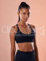 Fit, slim and serious woman feeling confident about her body and health while standing against a pink studio background. Portrait of a sporty and determined woman ready to exercise to stay in shape