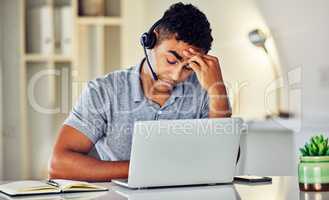 Stressed, tired and frustrated call center agent feeling sick or ill in the office while working on his laptop. A worried and unhappy young telemarketing employee suffering from a headache and pain