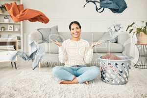 Portrait of a cleaning, carefree female cleaner throwing clothing in the air. Happy, smiling and young woman doing laundry, washing clothes and sitting in a messy living room at home.