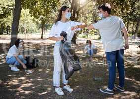 Covid, cleaning and volunteers wearing masks while cleaning a community park and saying thank you with a elbow gesture. Social disdancing between friends doing a cleanup outdoors during a pandemic