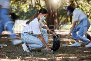 Volunteer, recycle and reduce waste by picking up litter, dirt and garbage outdoors in a park during covid. A young team of female NGO activists cleaning the environment during the covid19 pandemic