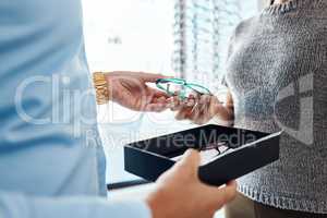 Vision, sight and treatment by an optometrist giving a woman a pair of glasses. Closeup of a female buying spectacles to help with blurry vision. Lady with bad or weak eyesight getting eyeglasses