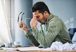 I need to take something for this splitting headache. a uncomfortable young businessman holding his forehead with his hand in pain while being seated at his desk at the office.