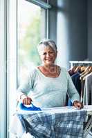 Creases are no match for me. Portrait of a mature woman ironing clothing at home.