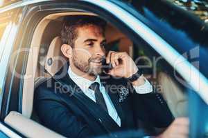 Making success happen from the comfort of his car. a handsome young corporate businessman on a call while commuting.