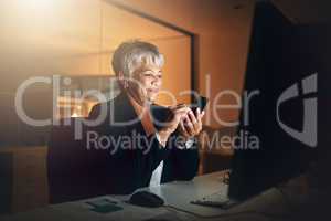 Connect around the clock. a mature businesswoman using a mobile phone at her desk during a late night at work.