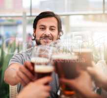 All together guys. a group of cheerful young business colleagues having a celebratory toast with beer around a table outside.