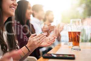 Lets give it a round of applause. a cheerful young group of business work colleagues clapping hands around a table at a restaurant outside.