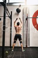 As heavy as it may be I will succeed. Rearview shot of a man working out with a ball in a gym.