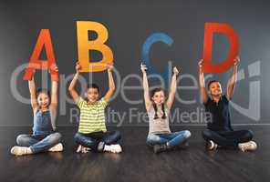 Now I know my ABC. Studio portrait of a diverse group of kids holding up letters of the alphabet against a gray background.