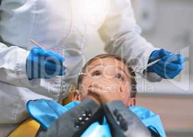 Do you promise that it wont hurt. a frightened little boy lying down on a dentist chair and holds his mouth closed to keep the dentist from working on him.